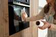© Pixel-Shot - Housewife wiping oven with paper towel in kitchen, closeup