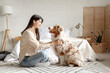 © Pixel-Shot - Young woman with Australian Shepherd dog sitting on floor in bedroom
