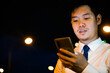 © sorapop - Stylish man suit using smartphone in neon-lit city street. Engaged in social media texting online shopping. Modern businessman communication success in night.