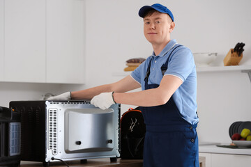 Poster - Male technician repairing electric oven in kitchen