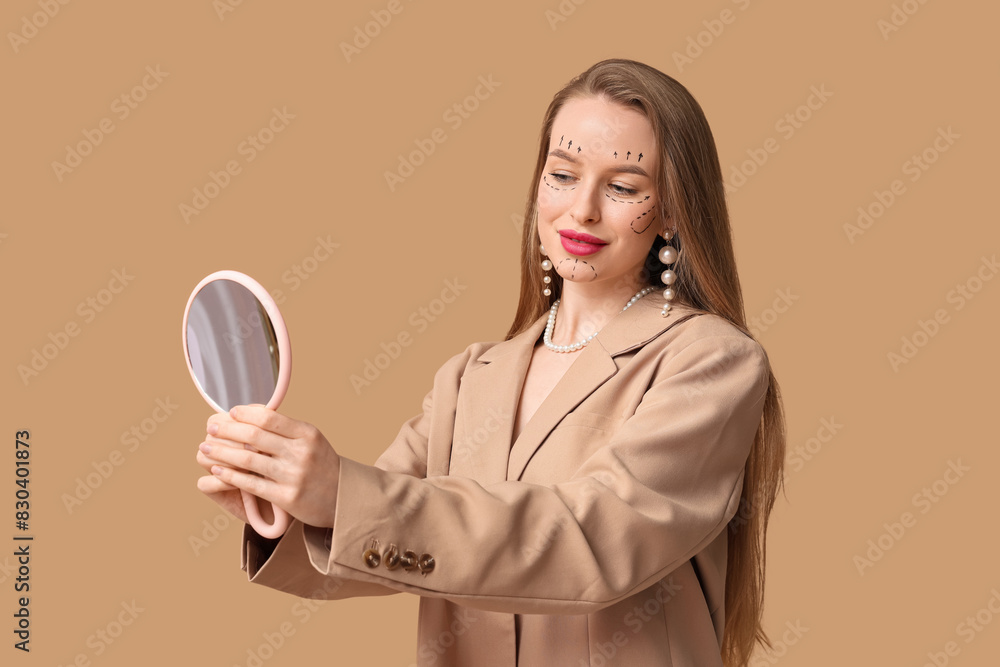 Young woman with marks on her face looking in mirror against beige background. Plastic surgery concept