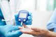 © manassanant - Asian doctor using digital glucose meter for check sample blood sugar level to treatment diabetes.