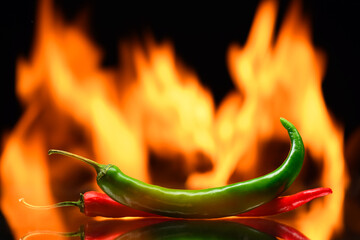 red and green chili peppers, on a background of burning fire, flames on a black background, hot and spicy spices