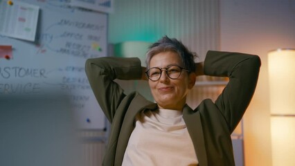 Business coach in her 50s pleased with finished online project, working late