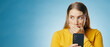 © peopleimages.com - Woman, shocked and reading with smartphone in studio, blog update and message notification on networking app. Social media, communication and promo for news or gossip, blue background and online