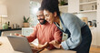 © peopleimages.com - Couple, man and woman with laptop on table for online research and reading blog, with support in home. Love, male and female person together with technology on desk for internet connection or bonding
