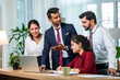 © StockImageFactory - Indian young businesspeople using laptop in group meeting at desk