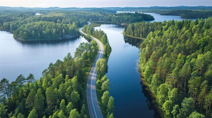 Wall Mural - Aerial view of a winding road cutting through lush green woods, flanked by serene blue lakes under the summer sun in Finland, highlighting the natural beauty.