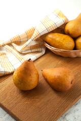 Wall Mural - Cutting board with pears, wicker basket and yellow kitchen towel on white wooden background..