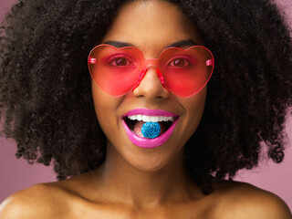 Wall Mural - Portrait, candy and woman in studio with retro fashion, heart glasses or afro on pink background. Quirky, makeup and female person with bright lips, smile or fun eyewear for cosmetics or accessories