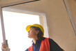 © Robert Kneschke - Young female construction worker wearing safety hardhat installing window frame at incomplete house