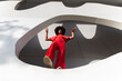 © VISTA by Westend61 - Mature woman with Afro hairstyle in red jumpsuit standing on white wall