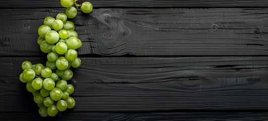 Wall Mural - Gray-green grapes on a black wooden surface. place for text. View from above. 