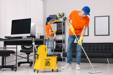 Wall Mural - Cleaning service workers cleaning in office. Bucket with wet floor sign indoors