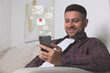© New Africa - Smiling man with smartphone chatting indoors. Many illustrations of envelope as incoming messages over device