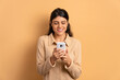 © Vergani Fotografia - happy young woman checking smartphone  in beige colors. app, social media, addiction, network concept.