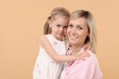 © New Africa - Family portrait of happy mother and daughter on beige background