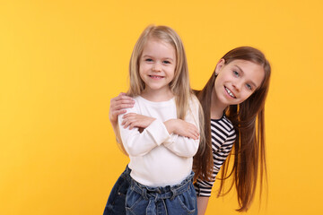 Sticker - Portrait of cute little sisters on orange background, space for text