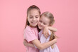 © New Africa - Portrait of cute little sisters on pink background