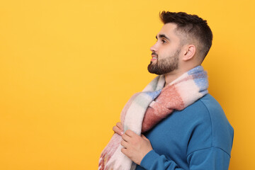 Wall Mural - Handsome man in warm scarf on yellow background. Space for text