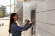 © Home-stock - Modern mail delivery concept. Woman with box at outdoor automated parcel machine choosing operation and touching screen