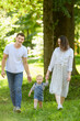 © GRON777 - Mom and dad hold their child hands while walking along grass in park on summer day. Happy family lifestyle concept.Happy family walking in nature,feeling of fun while spending time together.Vertical