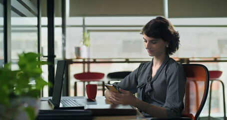 Business woman lady staff sitting chair hold mobile typing text order online food job office young adult gen z relax cute girl female use phone check email swipe photos social media spend break time