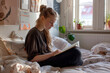 © LidiaLens - A blonde girl reading in her bed in her bedroom