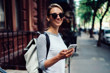 Wall Mural - half length portrait of young female leaving building for have a walk in downtown messaging via mobi