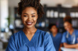 © Tanya - Smiling confident female African American doctor in blue uniform standing with her team in hospital. Medicine, healthcare concept.