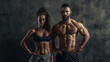 © OleksandrZastrozhnov - Athletic muscular man and woman standing against dark wall background.