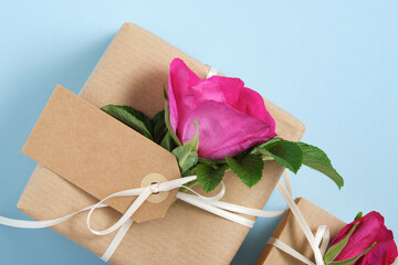 Wall Mural - Part of brown gift box with empty label and rosehip flowers on blue background. Space for your text