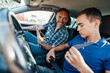 © Dusko - Driving instructor sitting in a car with his student and explain to him driving basics and traffic rules. He is using electronic tablet for education purpose. View from inside.