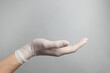 © New Africa - Doctor wearing white medical glove holding something on grey background, closeup