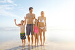 © Grady Reese/peopleimages.com - Blue sky, smile and family with children at beach in swimsuit for holiday trip, summer vacation or weekend getaway. Fun, happy parents and young kids for travel, adventure or bonding together at sea