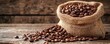 © worawut - Handmade burlap sack full of coffee beans on a wooden background with space for product presentation