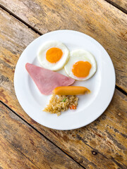 Canvas Print - Eggs with sausage in a plate on a wooden table