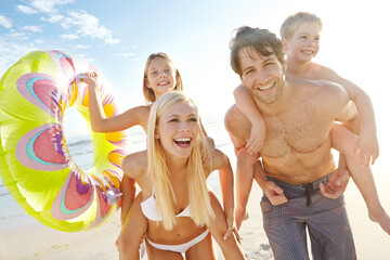 Wall Mural - Portrait, parents and children with piggyback on beach for vacation, holiday and trip in California. Outdoor, ocean and seaside with happy family, man and woman with daughter and son for bonding