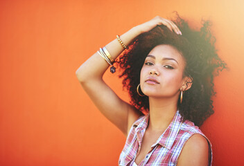 Wall Mural - Girl, confidence and portrait in fashion by wall with casual style, trendy outfit and mockup on orange background. Woman, person and attitude in city with streetwear, afro and pride in edgy clothes