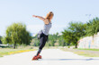 © Nikola Spasenoski - A young woman in striped top and rollerblades balances playfully on a sunny pathway in the park, exhibiting joy and active lifestyle.