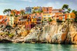 © apratim - A picturesque coastal town featuring vibrant, colorful houses built on a rocky cliffside, overlooking the serene Mediterranean waters.