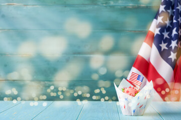 Patriotic cupcake 4th july with american flag. Delicious cupcake with cream cheese, blue, red star toping on old blue wooden background with lights bokeh. background. Dessert American Independence Day