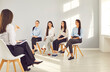 © Studio Romantic - Group of happy smiling business women company employees sitting on chairs in a row on a meeting and listening a woman leader speaking at the conference or seminar in the modern office.