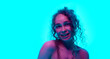 © master1305 - Happy, smiling, young woman with curly hair posing against cyan background in neon light. Spotless, well-kept skin. Concept of beauty, wellness, self-care, fashion, cosmetics