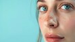 © olga_demina - Close-up side profile of a woman with blue eyes and freckles against a turquoise background. Beauty and skincare concept.