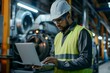 © anatolir - Focused engineer in safety gear using a laptop on the factory floor