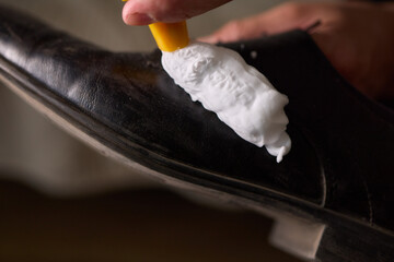 Wall Mural - A person is scrubbing a shoe with a sponge and foamy cleaner
