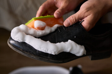 Wall Mural - A person is scrubbing a shoe with a sponge and foamy cleaner