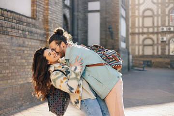 Passionate hipster couple is hugging and flirting on street at old town