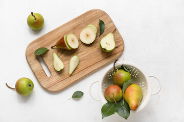 Wall Mural - Wooden board and colander with ripe pears on white table